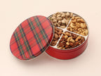 Photo of the mixed nut tin, showing a round tin with 4 sections that hold pistachios, cashews, almonds, and mixed nuts. The tin is round and red with a festive dark green plaid pattern.